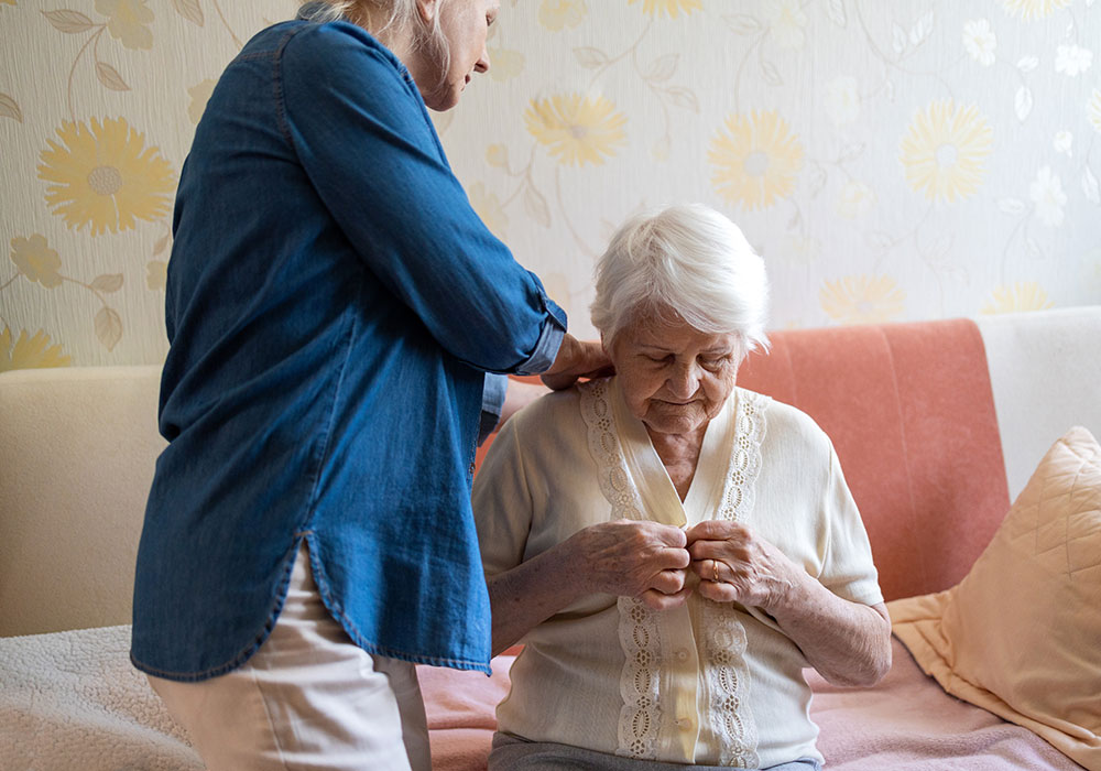 Dame âgée habillée par son aidante